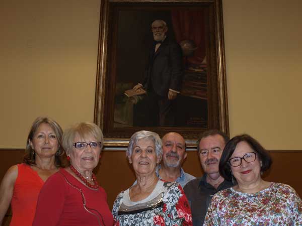 Pilar Altamira en el centro junto a los miembros de MAYMECO bajo el cuadra del "abuelo" Rafael Altaimira que hay en la Sede de Alicante de la UA